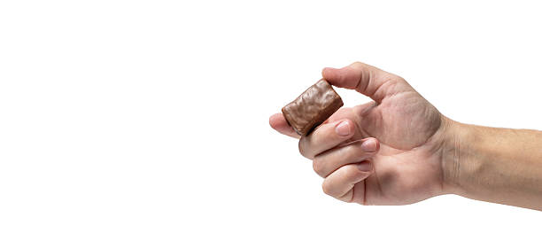 istock Man hand holding chocolate candy isolated on white background. 2232016226