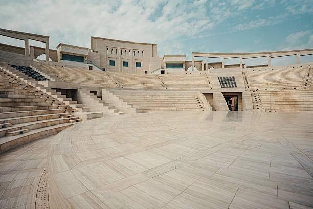 Empty amphitheater with stone seating and clear sky in the background.