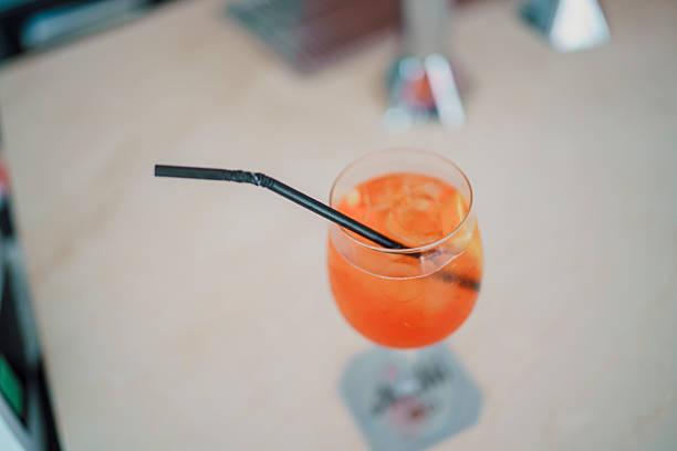 istock Chilled Spritz cocktail with ice cubes, orange slice garnish, sitting on bar surface alongside black straw, highlighting refreshing summer beverage 2232019446