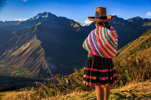 Peruvian woman spinning wool by hand in Sacred Valley, Peruvian Andes on the background. The Sacred Valley of the Incas or Urubamba Valley is a valley in the Andes  of Peru, close to the Inca capital of Cusco and below the ancient sacred city of Machu Picchu.
