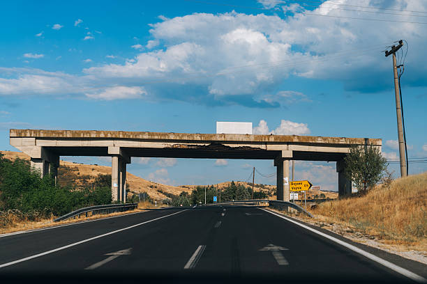 A highway with a bridge over it and a sign that says No Entry. The sky is blue with some clouds