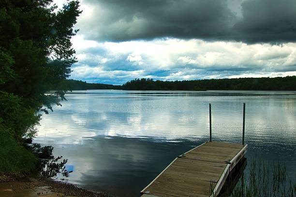 Early Summer view of a dock and the Flambeau River beneath dark clouds near Tony, Wisconsin.