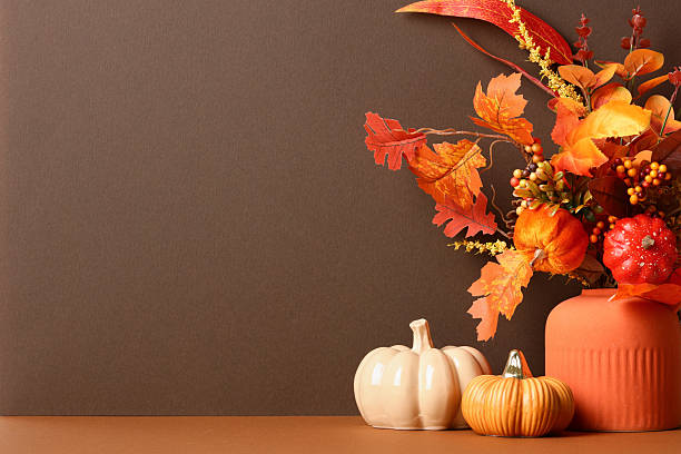 istock Autumn composition with ceramic pumpkins, orange vase, and vibrant fall foliage on brown background. 2232027455