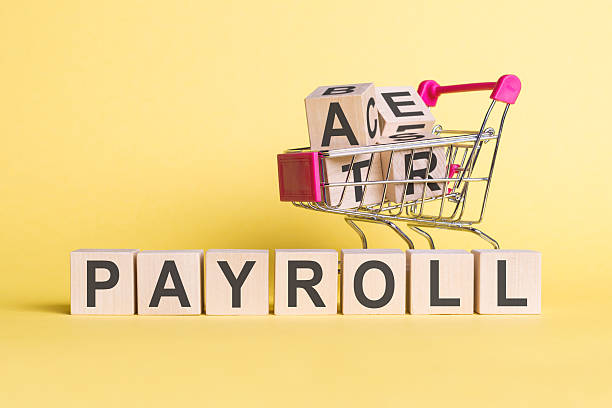 istock A miniature cart contains blocks with letters next to PAYROLL spelled out. 2232028841