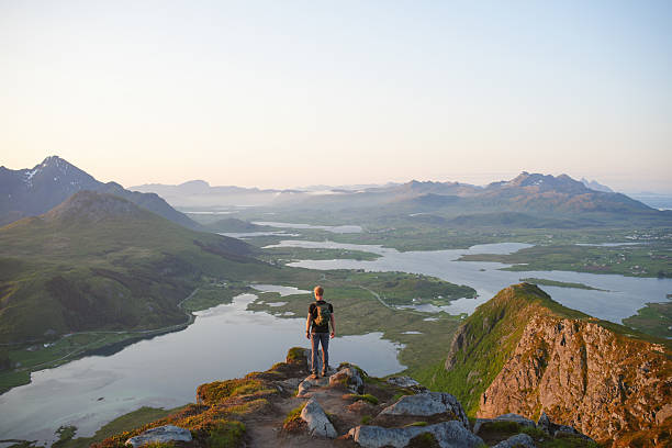 istock Young man on viewpoint above calm bay and islands at sunrise 2232045012