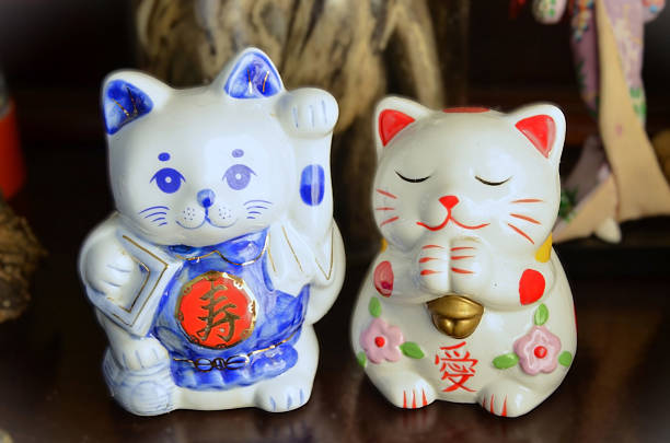 Two Japanese ceramic lucky cats Maneki Neko on the cabinet