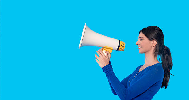 istock Woman enthusiastically speaking into a megaphone against a bright blue background during a public event sharing ideas and messages with passion 2232051795