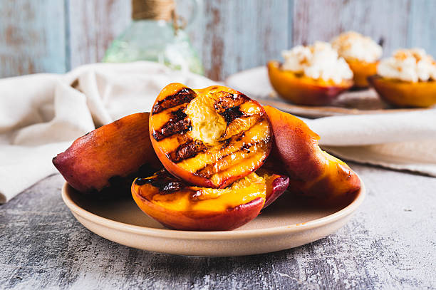Delicious grilled peach halves on a plate on the table closeup