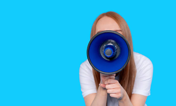 istock Woman holding blue megaphone against solid blue background calling for attention in a public speaking event at a community gathering in the afternoon 2232056290