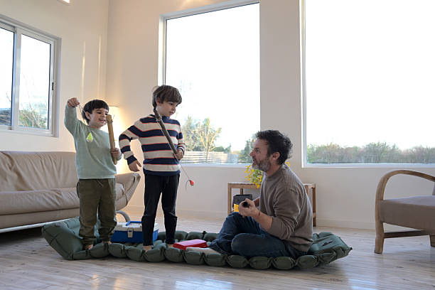 dad and his sons playing sailors with a mat in the living room