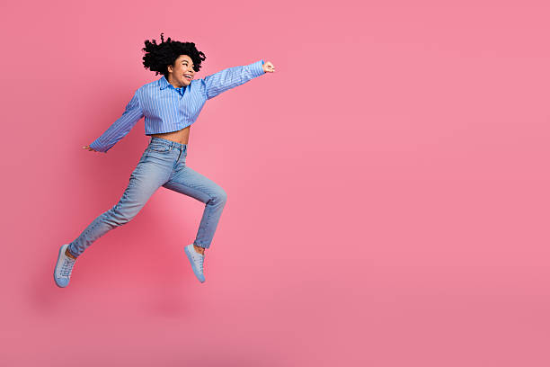 istock Joyful young woman jumping dynamically against a pink background, expressing energy, happiness, and a carefree lifestyle 2232056794