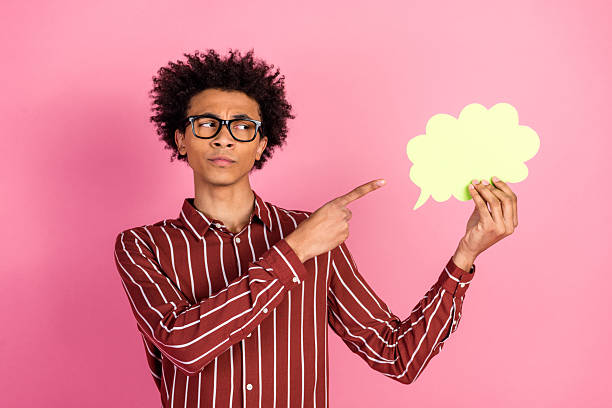 istock Stylish young man pointing to a text bubble on a pink background, expressing curiosity with a thoughtful gesture 2232057154