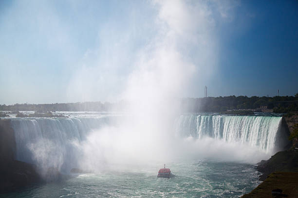 On the Niagara River heading into the mist of the falls with buildings in Canada on the cliffs