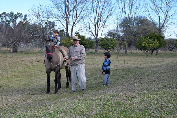 grandfather taking his nephews for a ride on horseback in the countryside