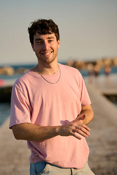 Cheerful young man smiling while enjoying a beautiful sunset at the beach, embodying the carefree spirit of summer and relaxation