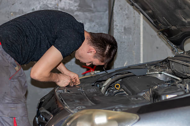 istock A young man unscrews a headlight bulb inside the hood. 2232064930