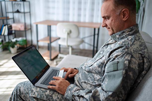 istock Soldier using laptop and credit card making online purchase at home 2232070369