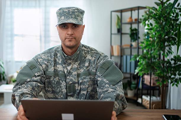 istock Soldier wearing camouflage uniform using laptop at home 2232070602