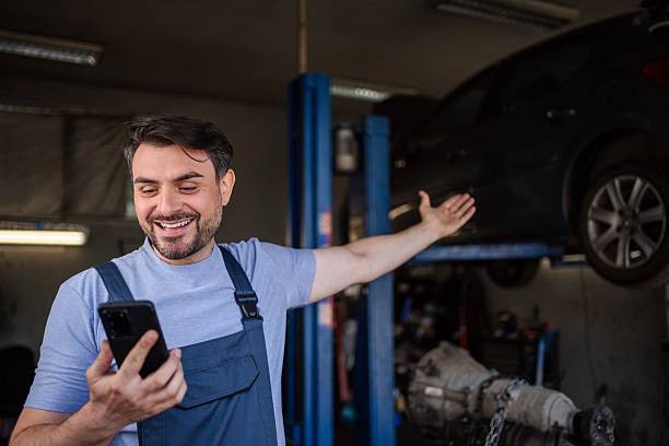 istock Happy mechanic showing a lifted car while using a smartphone in a garage 2232070851