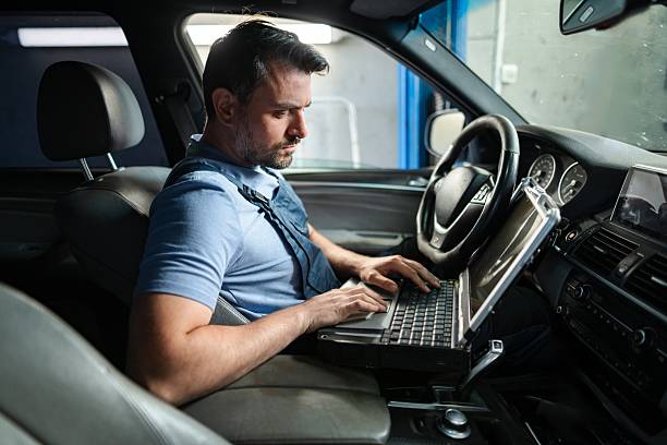 istock Car mechanic using laptop for diagnostics inside vehicle in auto repair shop 2232070874