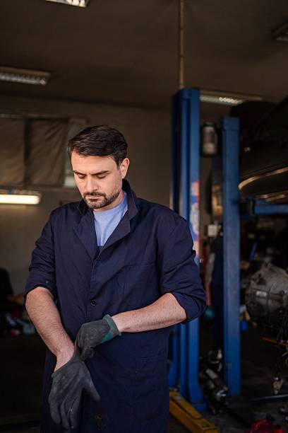 istock Car mechanic putting on work gloves in his garage 2232071364