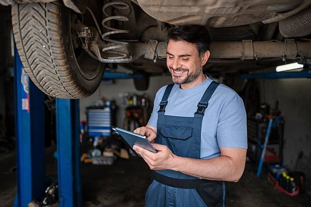 istock Car mechanic using a digital tablet while inspecting a lifted car in a repair shop 2232071412