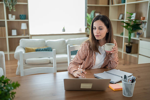istock Focused freelancer working remotely from home office enjoying coffee 2232072008