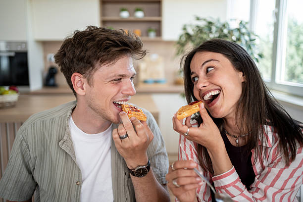 istock Cheerful couple eating waffles with jam in the kitchen 2232072279