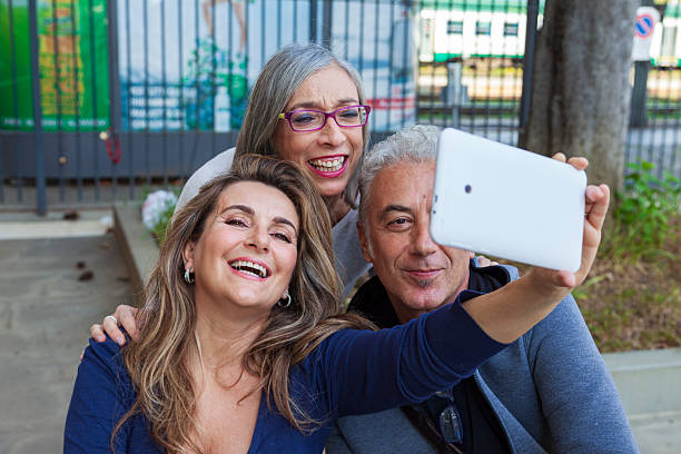 istock Three smiling mature adults are embracing while taking a selfie with their smartphones 2232072591