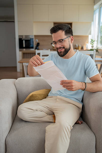 istock Happy man opening envelope and reading letter at home 2232072827