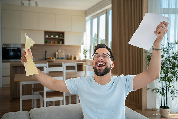 istock Excited man celebrating success holding documents at home 2232072884