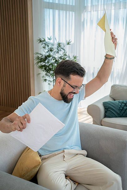 istock Excited man celebrating success with documents at home 2232072964