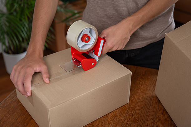 istock A boy packs and seals a cardboard box with tape 2232075257