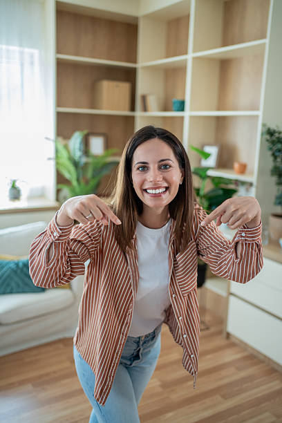 istock Young woman pointing down with both index fingers and smiling 2232075923