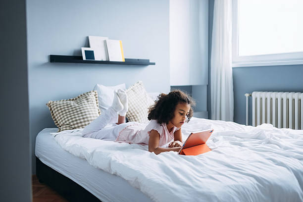 istock Girl Relaxing at Home and Using a Tablet Device on a Cozy Bed 2232075962