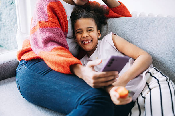 istock Happy Mother and Daughter Bonding on Couch Viewing Phone Content 2232076000