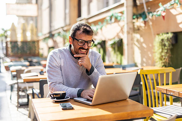 istock Freelancer working on laptop at outdoor cafe, enjoying a coffee 2232077468