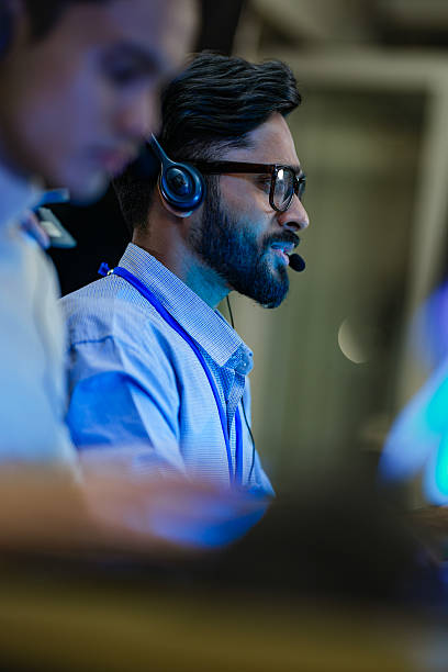 istock Professional call center agents with headsets providing friendly customer support. A dedicated male operator and his team work in a modern 24/7 technical assistance center. 2232077554