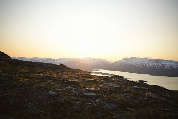 Midnight sun over lake and snowcapped mountains, Abisko National Park