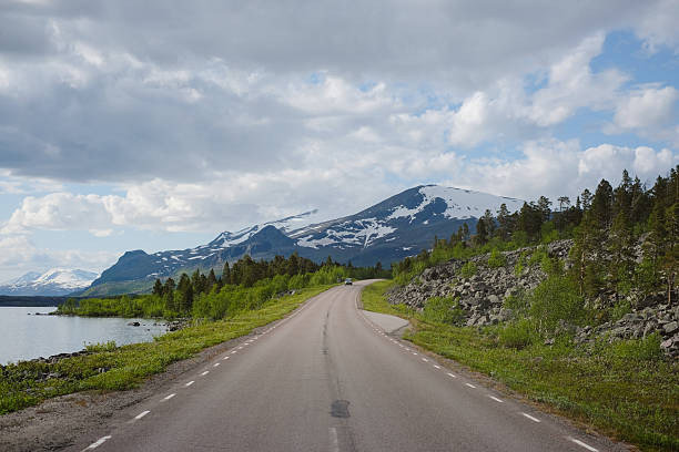 Highway along lakeshore and snowcapped mountain, Lake Akkajaure, Stora Sjöfallet National Park