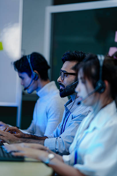 istock A technical support team works a late shift in a modern call center. A male agent points at his screen, guiding a client or training a colleague on a complex technical issue. 2232079315