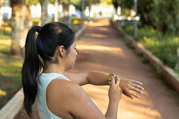 istock Focused female athlete tracking fitness data on smartwatch while exercising outdoors, wearing ponytail, evaluating training performance in green urban park setting 2232083243