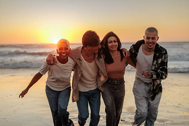 istock Happy friends walking on the beach at sunset 2232084625