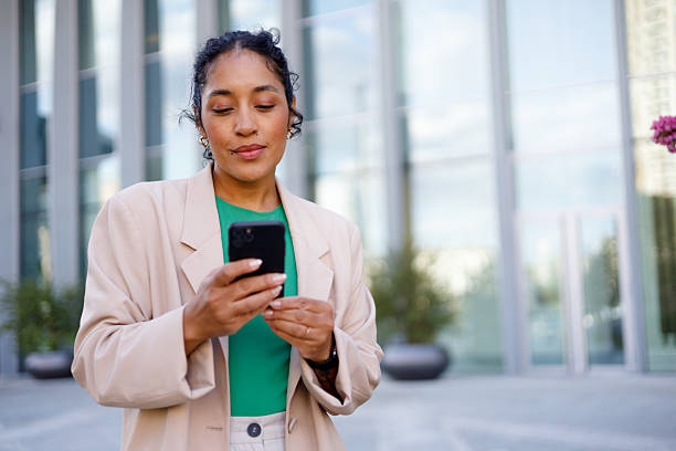 istock Young businesswoman using a smartphone while standing in front of a modern office building, embodying professionalism and confidence 2232086600