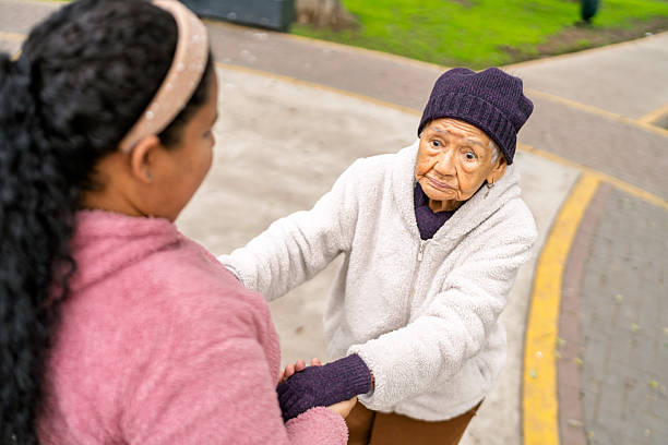 Nurse assisting elderly woman while walking in park