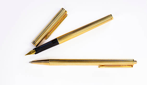 Golden pen and mechanical pencil lying on white background