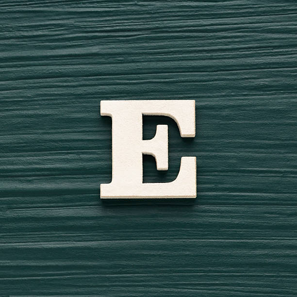 istock Alphabet letter E, white piece on a dark green rustic background 2232107235