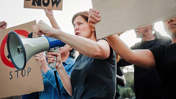 istock Multicultural urban protest for immigrant rights, fists raised, diverse group holding signs in city 2232111333