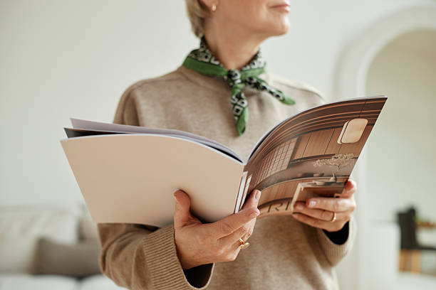 istock Caucasian Senior Woman Reading Magazine While Standing Indoors 2232116123