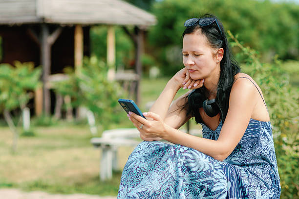 istock Woman sitting outdoors looking at smartphone 2232120055